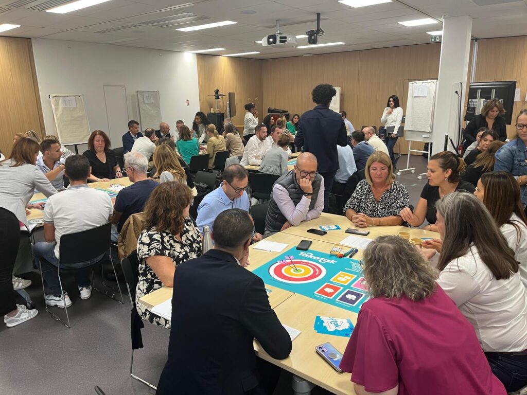 Plusieurs groupes de salariés jouent au Takotak diversité dans une salle, répartis par groupes à des tables