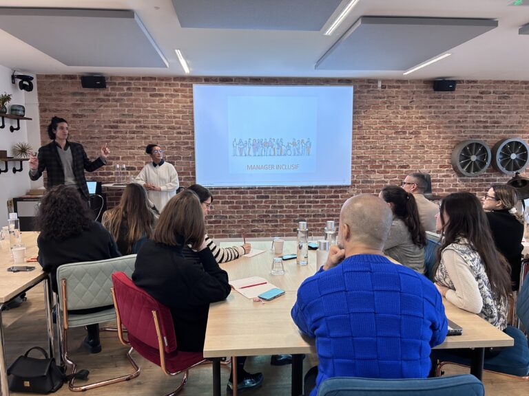 Un groupe d'apprenants assis à une table écoutent Jawad dispenser la formation Manager inclusif