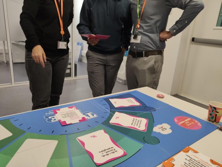 3 salariés jouent à Top Five, l'animation sur la santé mentale, le plateau est posé sur une table au premier plan